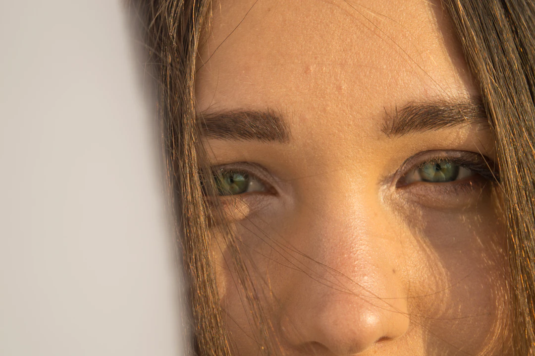 Close-up of a woman's green eyes and brows in warm light